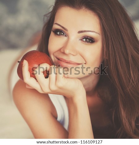 Portrait of lovely young woman holding a fresh ripe apple and smiling