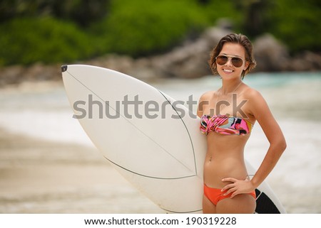 Beautiful Young Woman Surfer Girl in Bikini with Surfboard at a tropical Beach