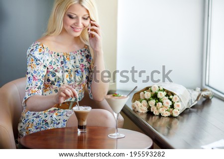 portrait of happy young blonde woman talking on the cell phone in a cafe. Smiling beautiful woman