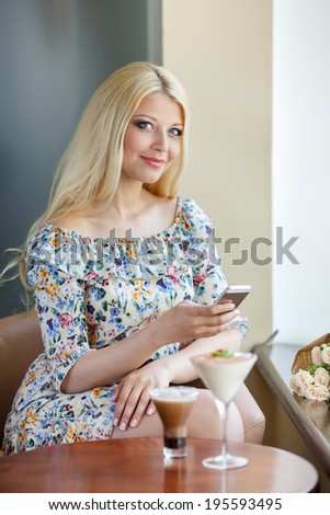 Young beauty woman writing message on cell phone in a street cafe. Looking down