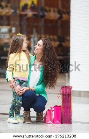 Young mother and her daughter doing shopping together. Shopping mall. Shopping bags.
