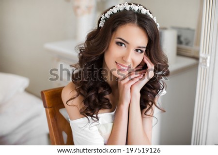 Beautiful young bride with wedding makeup and hairstyle in bedroom, attractive newlywed woman have final preparation for wedding. Happy Bride waiting groom. Marriage Wedding day moment. Bride portrait