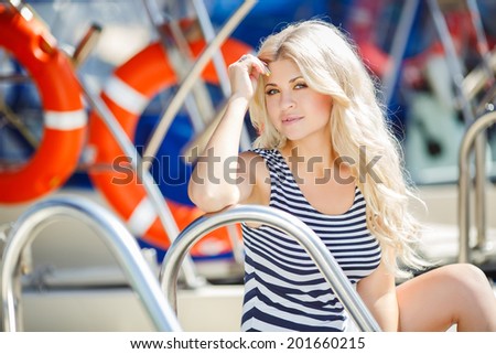 Beautiful sexy woman wearing sailor striped dress posing at the sea. Adorable woman wearing sea Captain's cap and sexy sailor T-shirt