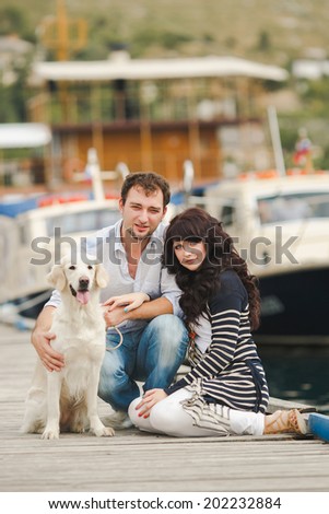 Young couple with dog posing at historical town sunny day. Couple playing with their dog in harbor