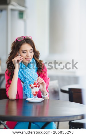 young beautiful woman eating a dessert and talking on the phone. Spending time at the restaurant. Attractive young woman drinking coffee at the restaurant and talking on the phone