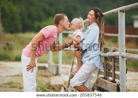 Portrait of a Young happy family having fun at countryside outdoors. Summertime. Family feeding Horses on the meadow