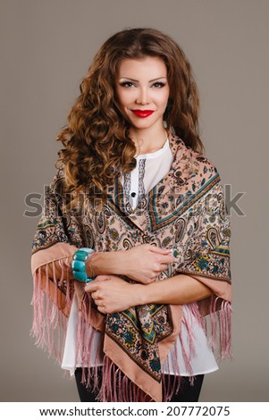 beautiful oriental look young woman with scarf on green background. portrait of a beautiful young woman with a scarf on her shoulders. Russian beauty. Russian national traditional scarf. Studio shot