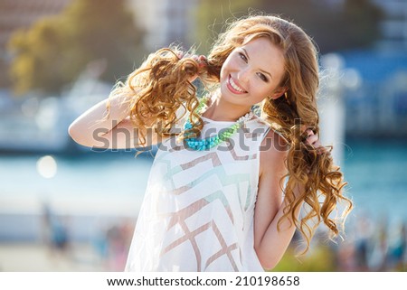 Beautiful young woman with long hair pictured turning head as beams of light capture moisture and mist in air. Portrait close up of young beautiful woman, on green background summer nature.
