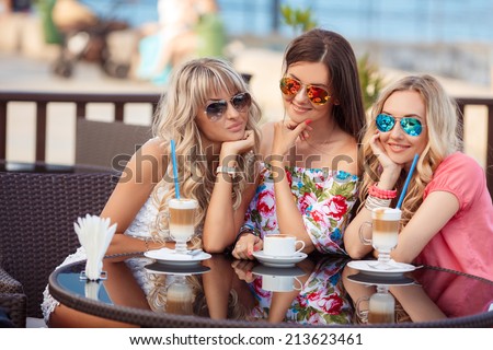 Group Of Women Meeting In Cafe. holidays, tourism, technology and internet - three beautiful girls. Three Women Enjoying Cup Of Coffee In Cafe.