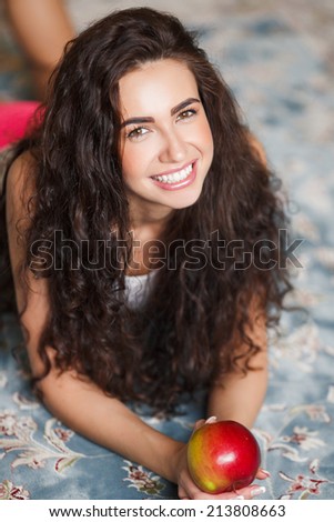 Portrait of lovely young woman holding a fresh ripe apple and smiling. Apple woman. Very beautiful ethnic model eating red apple