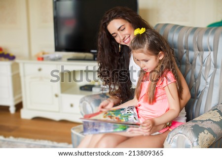 family, children, education, school and happy people concept - mother and daughter with book. young mother and her daughter lie on the floor and reading a book