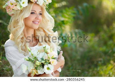 Beautiful young blonde woman in white dress and flower wreath with swing in summer outdoors. Woman outdoor. Summer portrait. Blonde girl in flowers.