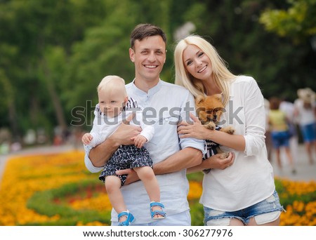 happy family having fun outdoors. Mother, father, child boy and dog having fun in green park.