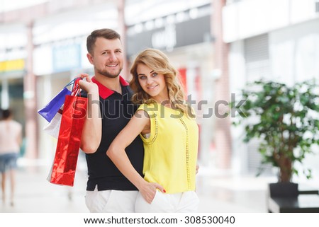 Couple - man and woman - in a shopping mall with colorful bags simply having fun. Portrait of happy couple with shopping bags. happy young couple with bags in shopping centre mall