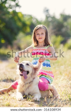 child girl with labrador retriever in park. Little girl hugging retriever in the field,
