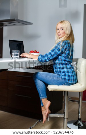 Happy Young Beautiful Woman Using Laptop, Indoors. Happy pretty woman using laptop sitting by the table. Woman netsurfing