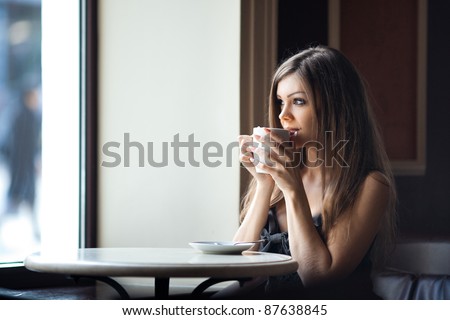 Beautiful young woman with a cup of tea at a cafe