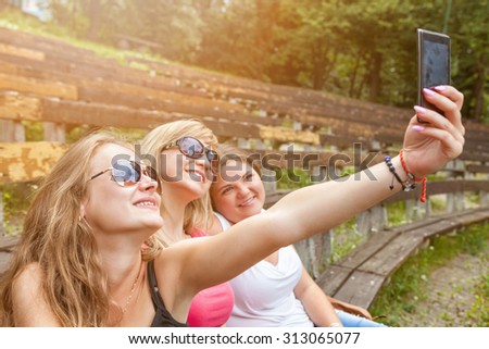 Group of friends taking a selfie with a smart phone outdoors