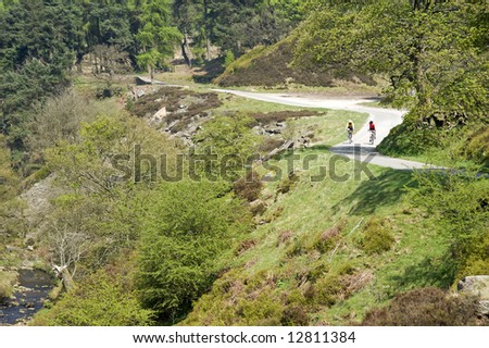 cyclists cycling along road in the goyt valley the peak district national park derbyshire england uk
