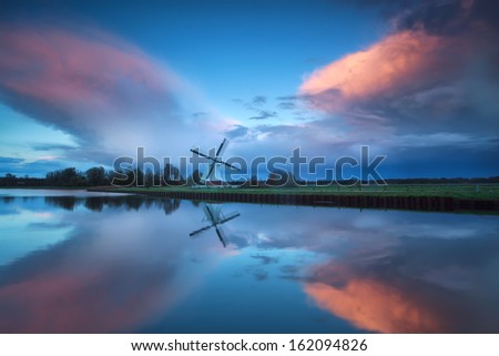 dramatic stormy sunset over Dutch windmill and river, Groningen, Netherlands