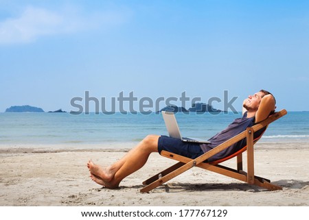 happy business man with laptop relaxing on the beach