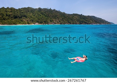 travel insurance concept, man swimming in lifebuoy on paradise beach