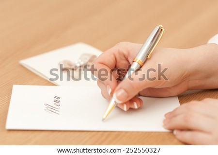 Woman writing on a wedding menu.