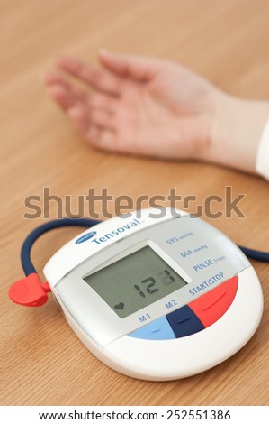 Zagreb, Croatia - January 31, 2015: Woman checking blood pressure and heart rate with a Hartman Tensoval digital blood pressure monitor.