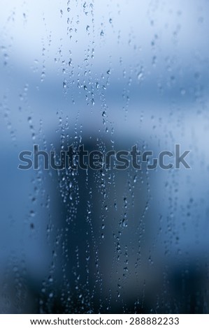 Drops of rain on a window pane, buildings in background.