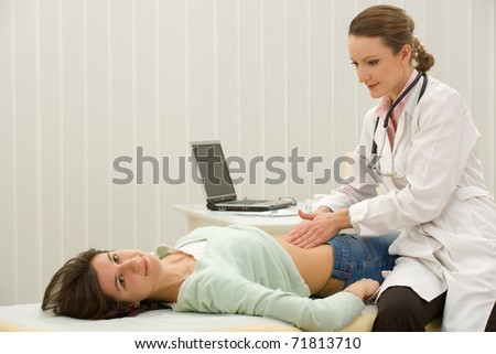 Woman doctor examining the patient - young woman lying on couch