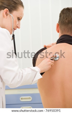 Doctor listening to man\'s heartbeat in office