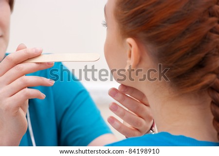 Woman doctor examines a throat of young woman