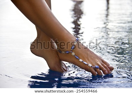 Female feet above the water with bracelet on ankle