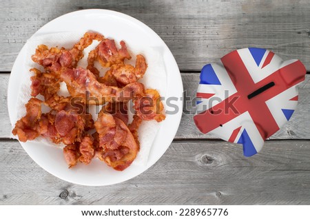 Bring home the bacon concept piggy bank overlaid with UK flag against wooden background