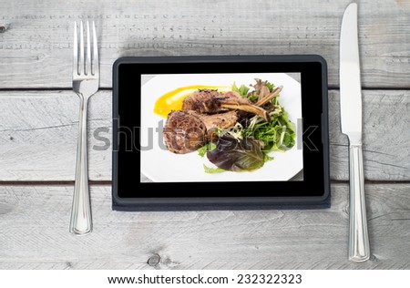 Online ordering food concept with table setting and meal course on a tablet screen
