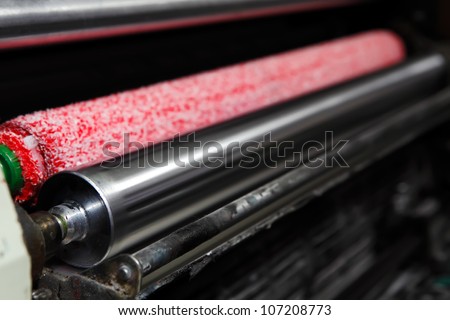 Opened offset printing machine with ink rollers with special red wetting roller. Focused to left side image.
