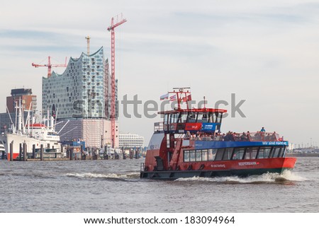 HAMBURG, GERMANY - MARCH 20, 2014: Construction of the landmark Elbe Philharmonic building rises behind public harbor ferry \