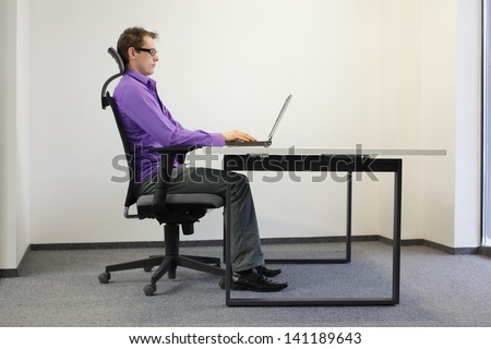 correct sitting position at workstation. man on chair working with laptop