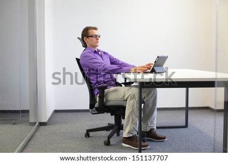 correct sitting position at workstation. man on chair working with tablet