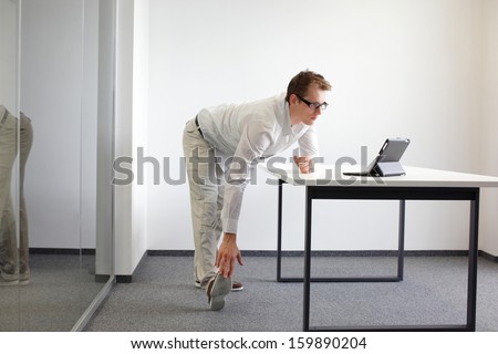 Exercises during office work - standing man reading at tablet in his office