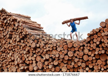 man on top of large pile of logs, lifting heavy log - training