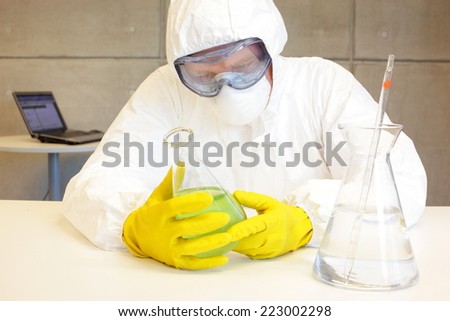 scientist in protective uniform,goggles,mask,gloves working  in lab with glassware