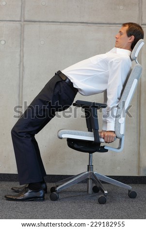 office occupational disease prevention -business man exercising on chair  - profile view