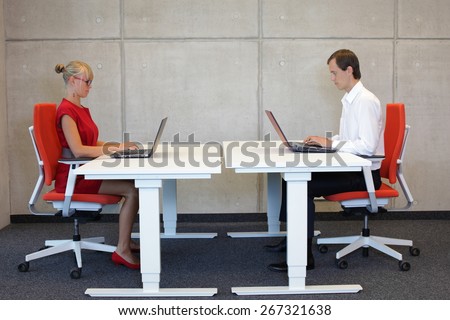 business man and woman in correct sitting posture at workstations in the office