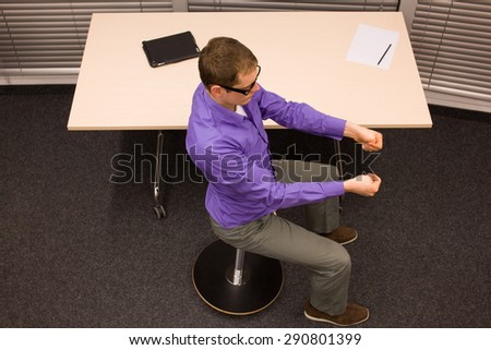 male office worker,exercising during short break in work at his desk in office