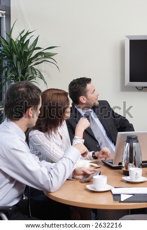 Two men and one woman business professionals at a meeting.