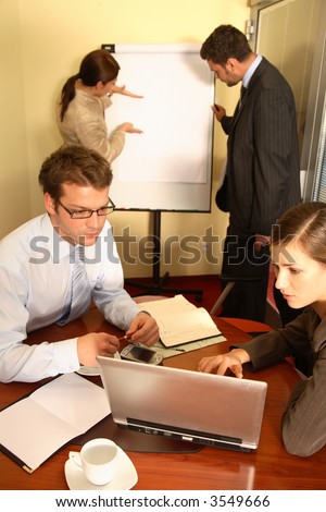 A business team of two men and two women, work on putting together a business proposal for a client.