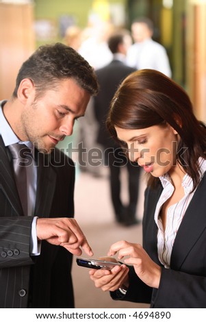 A businessman explains how to use a cellphone as an appointment calendar to his female partner.