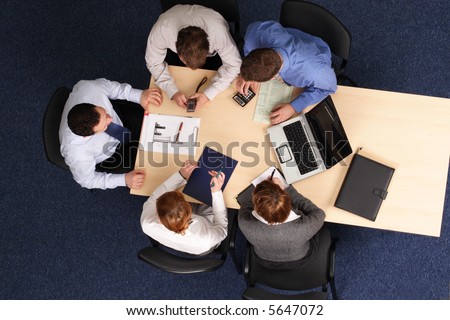 five business people meeting - Businesspeople gathered around a table for a meeting, brainstorming. Aerial shot taken from directly above the table.