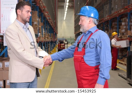 manager and senior worker handshake in warehouse